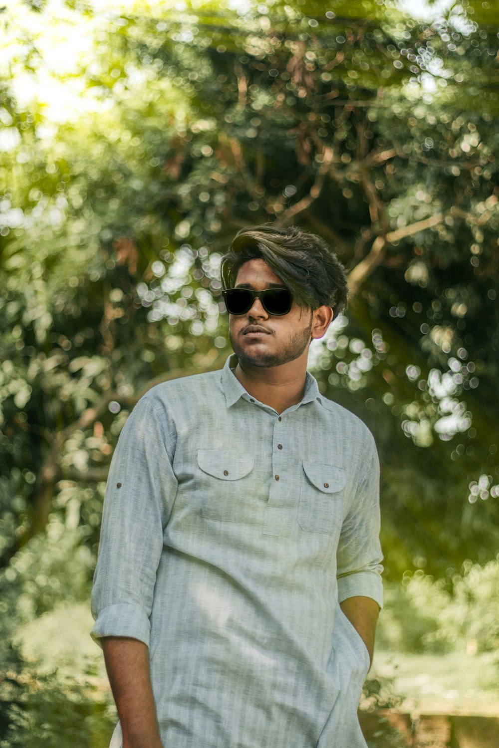 a man in sunglasses standing in front of a tree