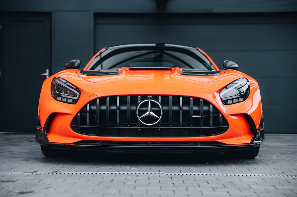 an orange sports car parked in front of a garage