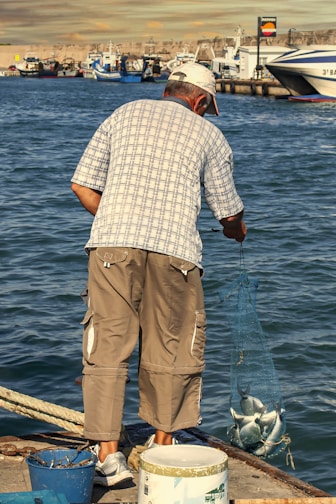a man standing on a dock holding a fish