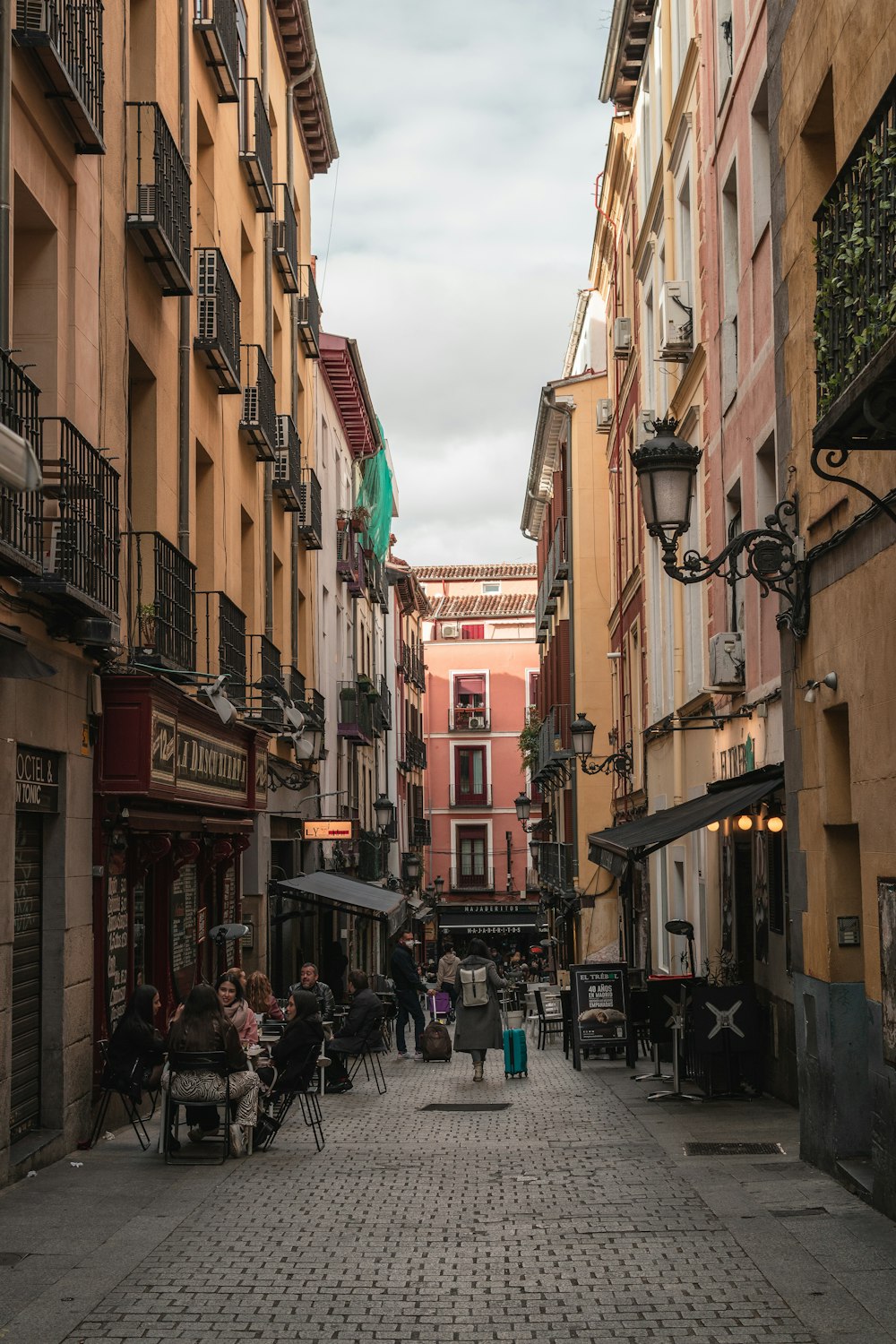 a cobblestone street lined with buildings and people sitting at tables