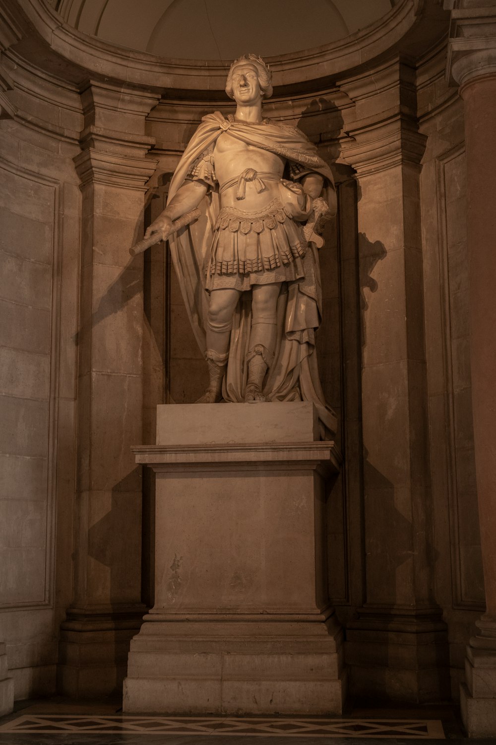 Eine Statue eines Mannes mit einem Umhang in einem Raum