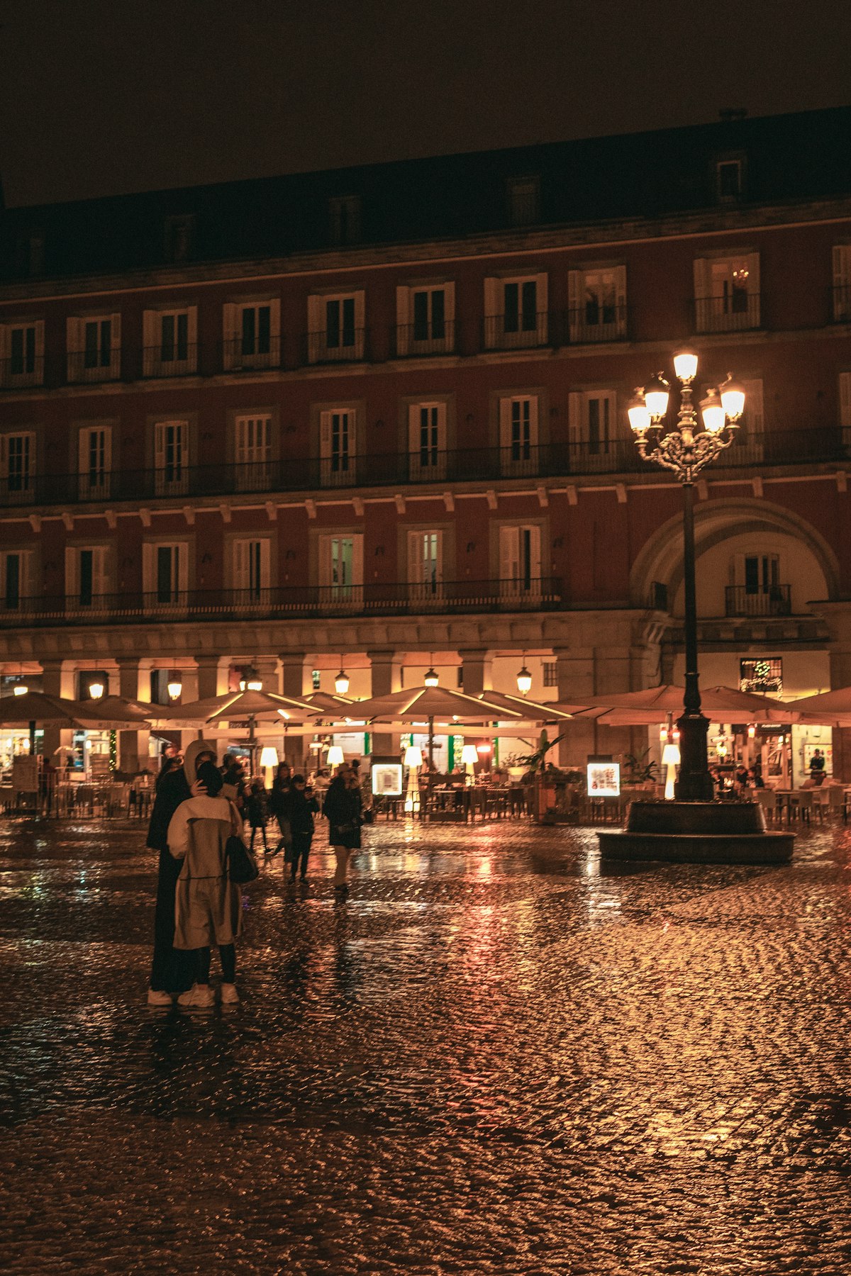 Plaza Mayor em Madrid à noite, com pessoas caminhando