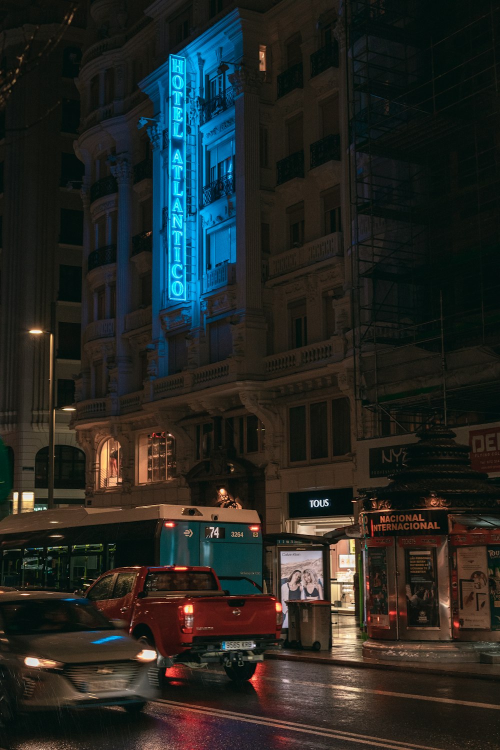 a city street at night with a large building lit up in blue