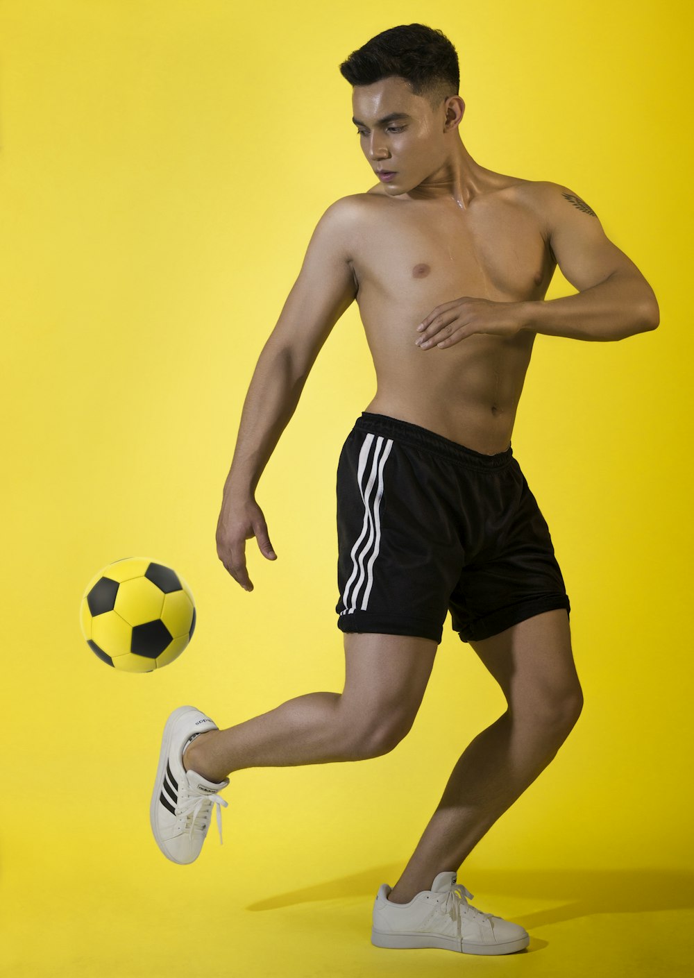 a shirtless man kicking a soccer ball