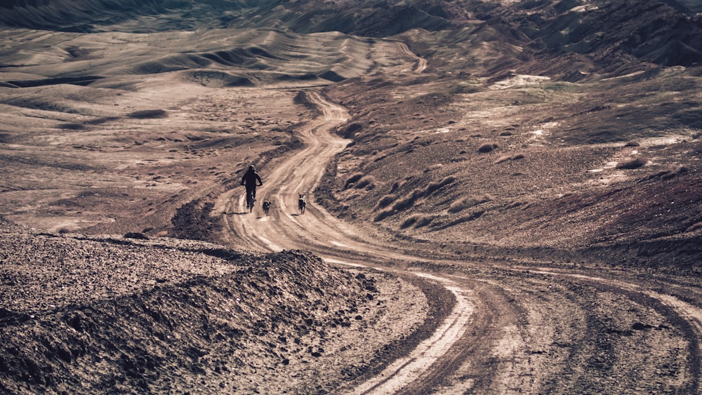 a man riding a bike down a dirt road