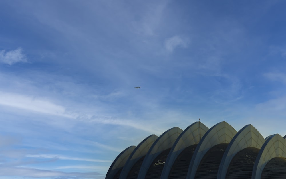an airplane flying over a building under a blue sky