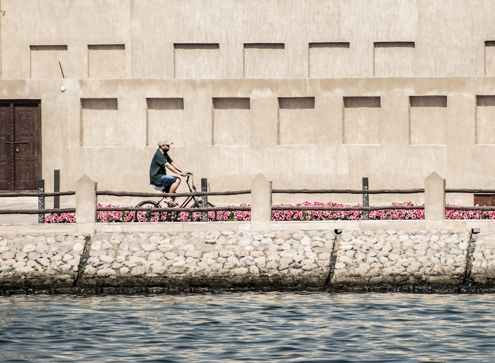 a man riding a bike down a street next to a body of water