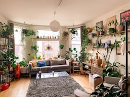 a living room filled with lots of plants and furniture