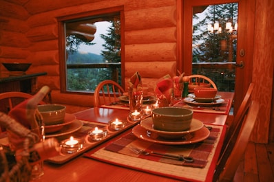 a dining room table set with place settings and candles