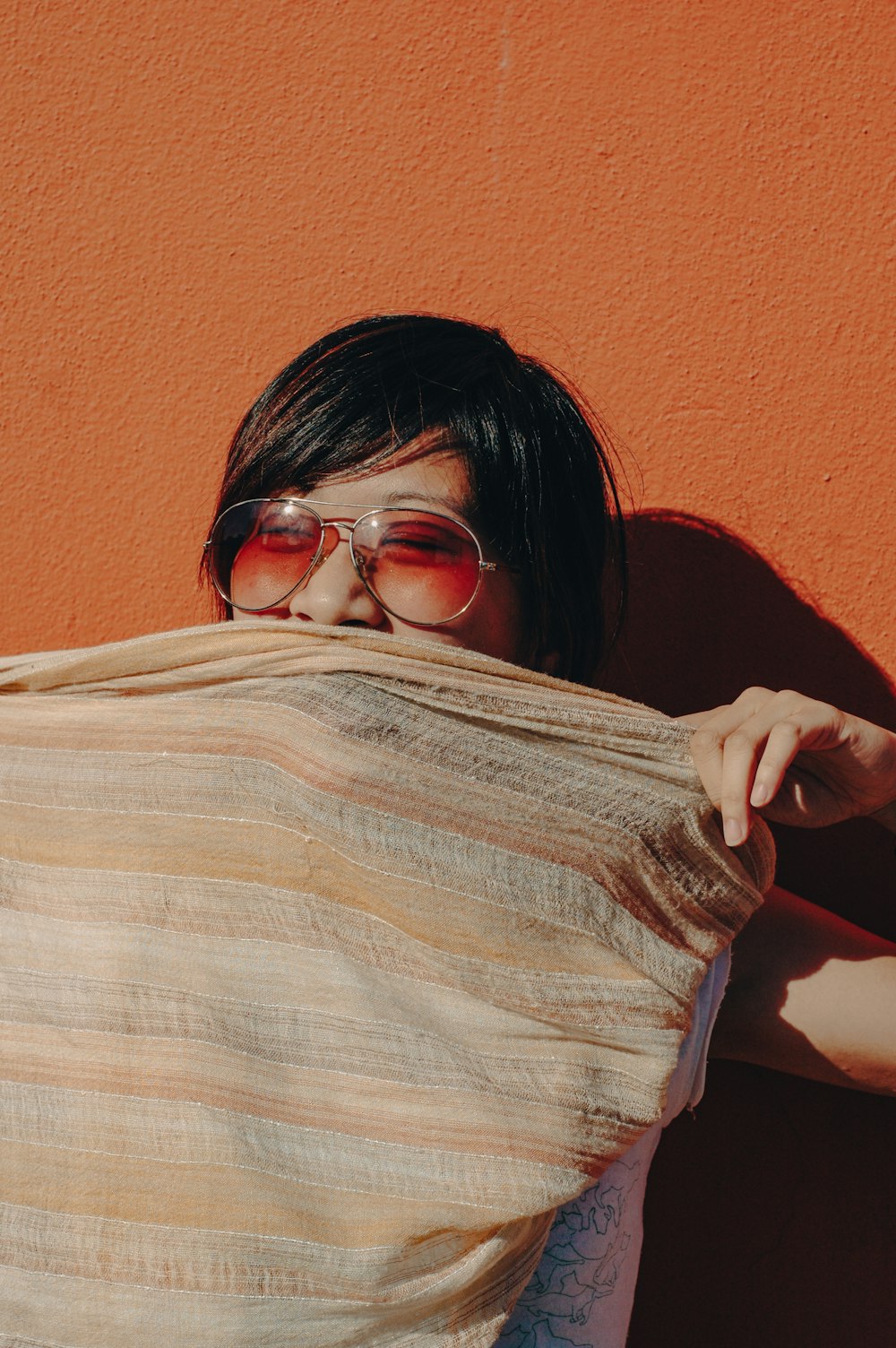 a woman wearing sunglasses covering her face with a blanket