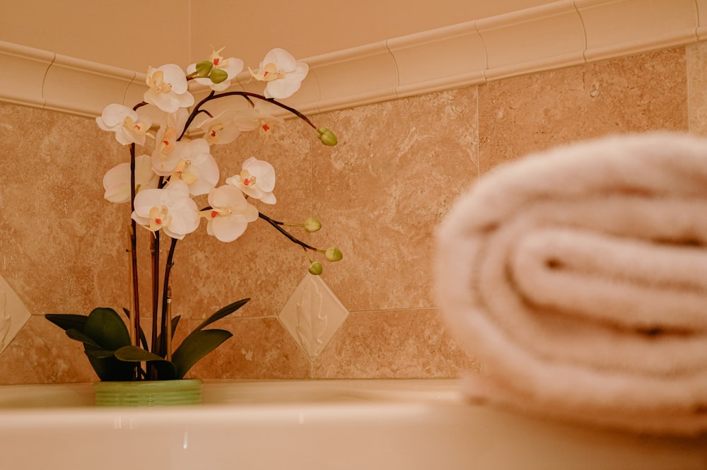 a vase with flowers and towels in a bathroom