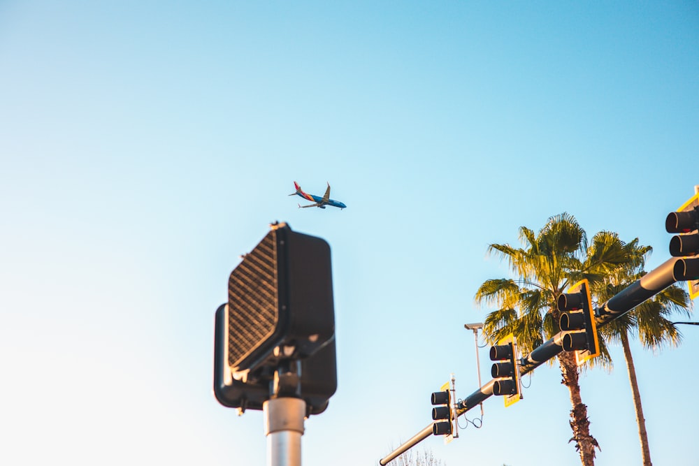 an airplane flying over a traffic light and palm trees