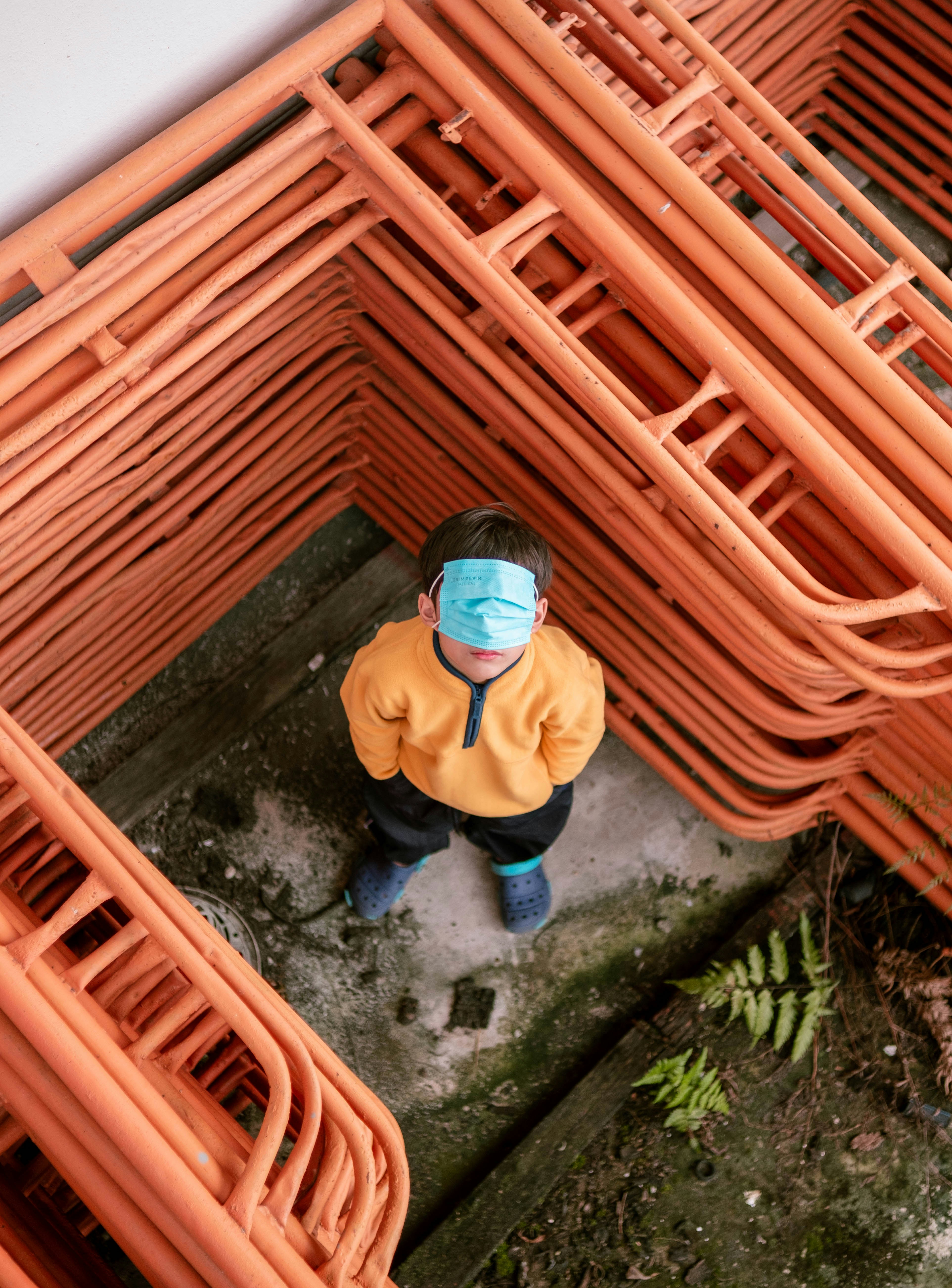 a person wearing a face mask standing in front of a pile of orange wicker