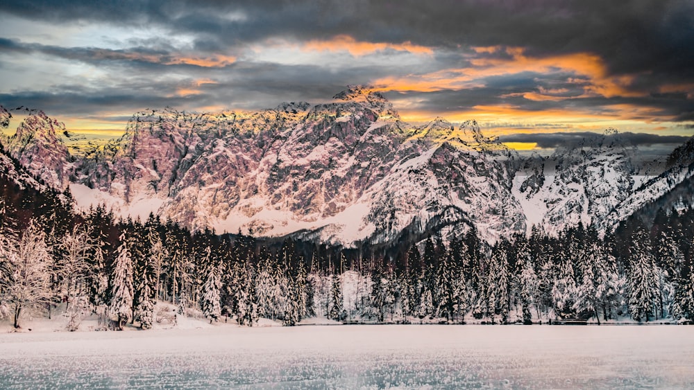 a mountain range covered in snow under a cloudy sky