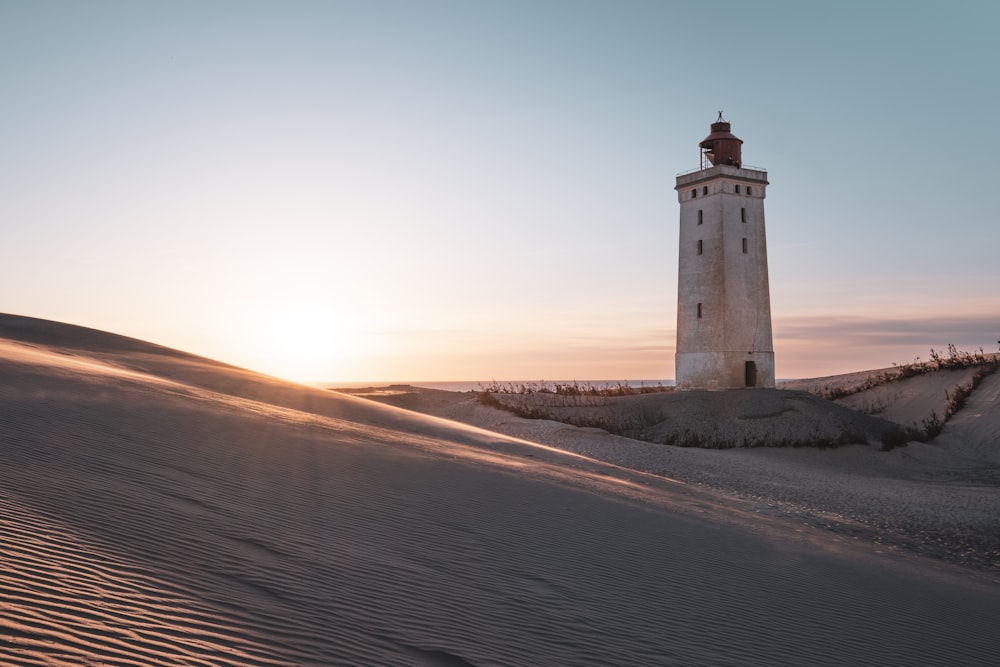 a light house sitting on top of a sandy hill