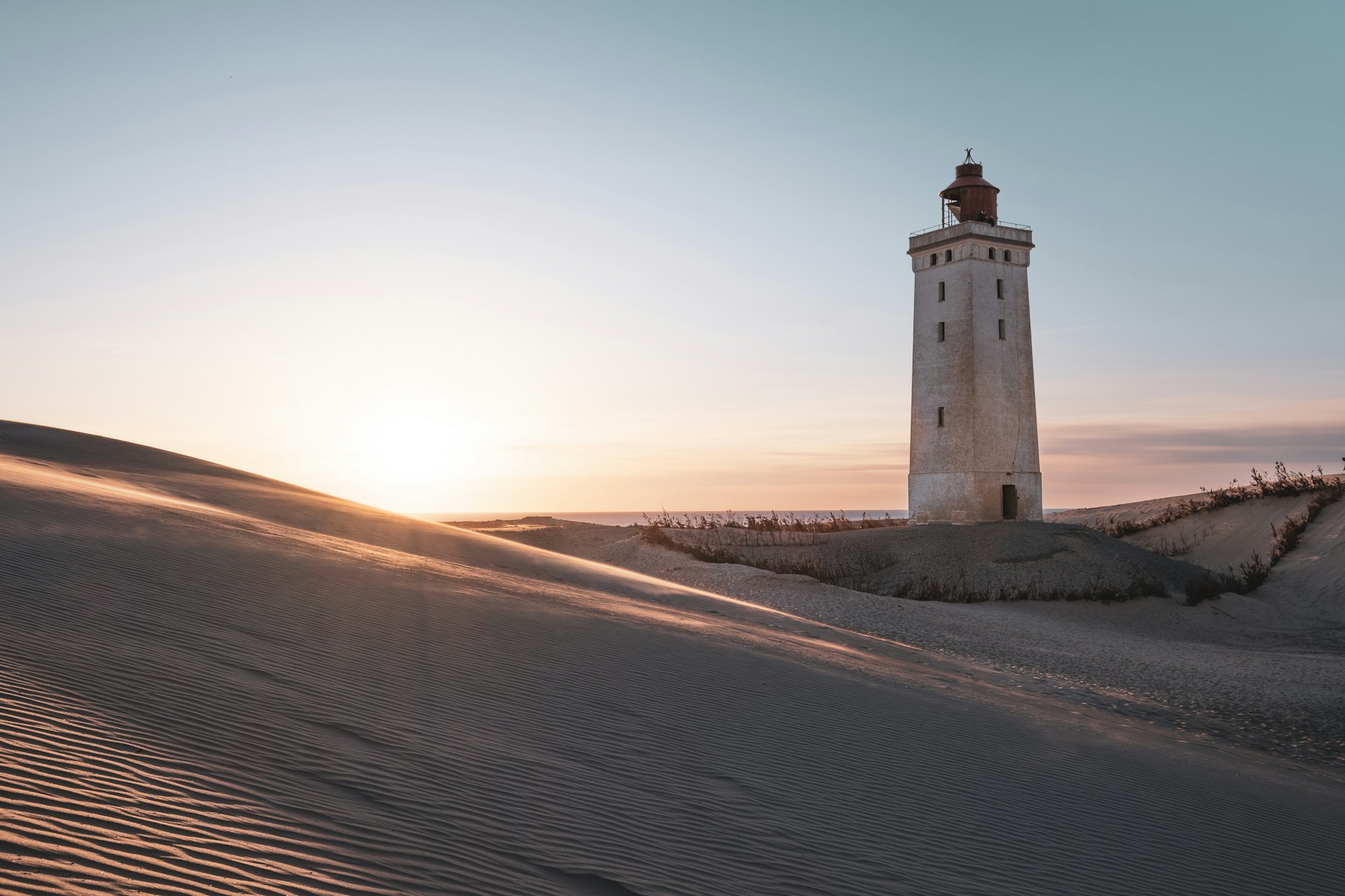 a light house sitting on top of a sandy hill
