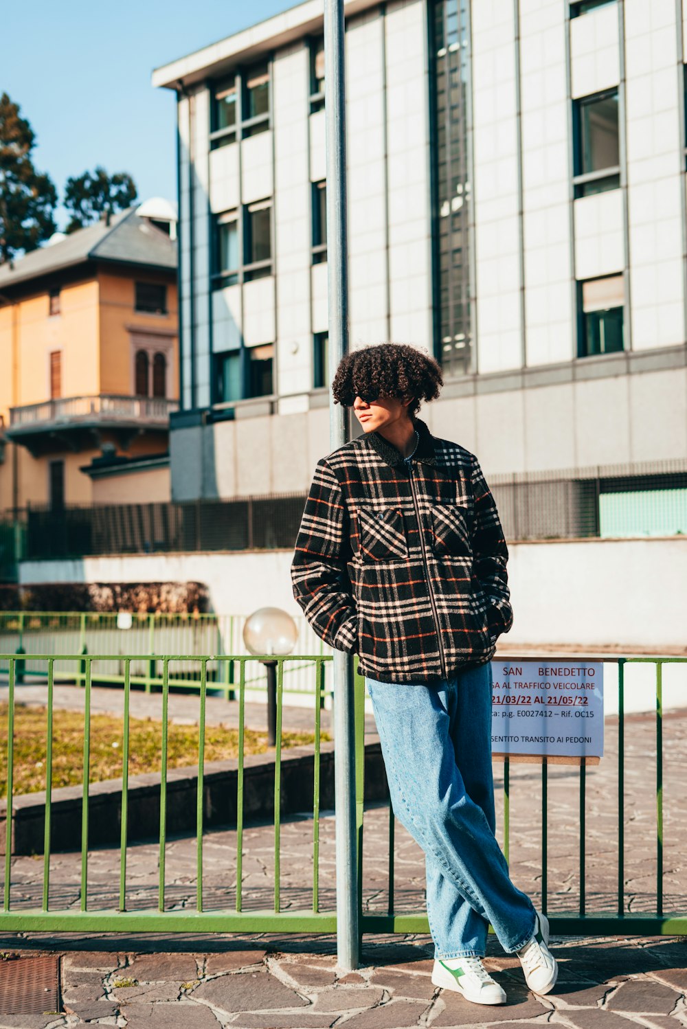 a man standing on a sidewalk next to a fence