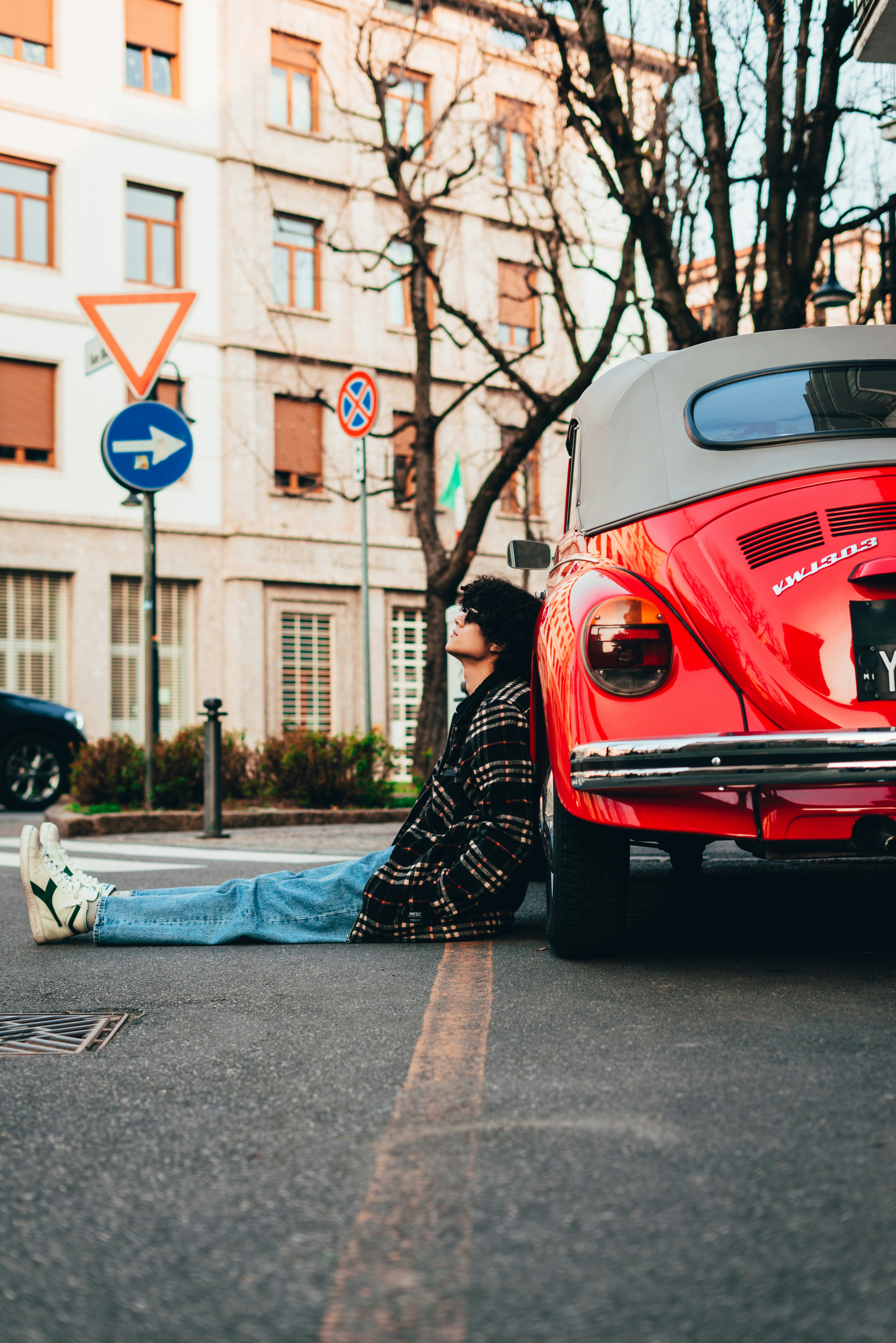 Un hombre tendido en el suelo junto a un coche rojo