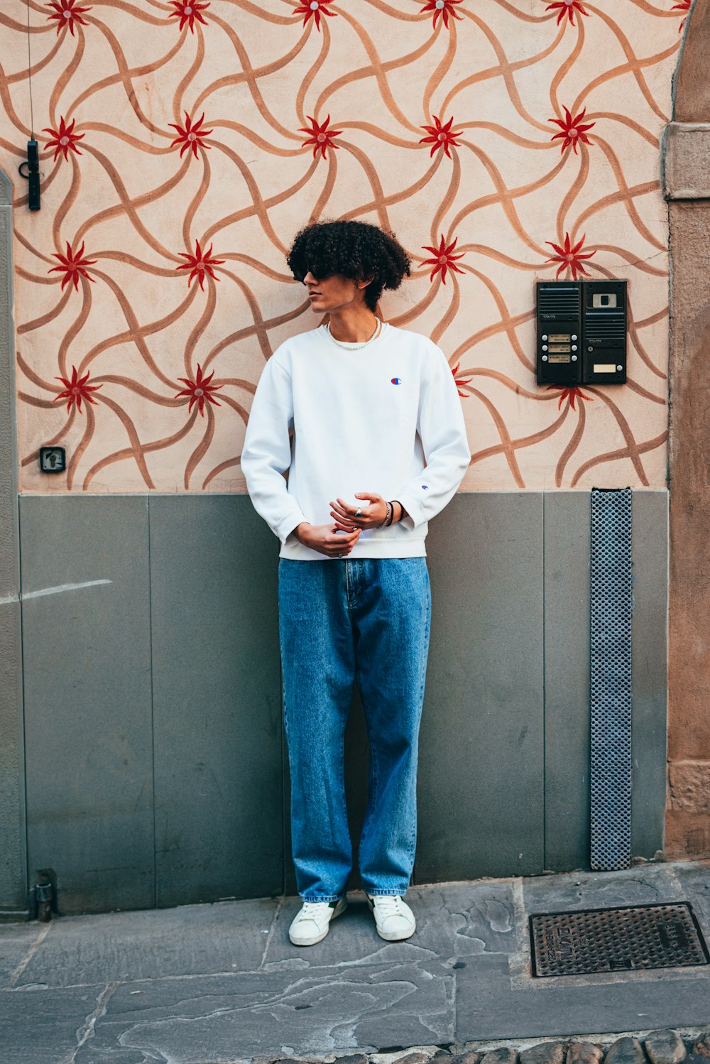 a man standing against a wall with his hands in his pockets