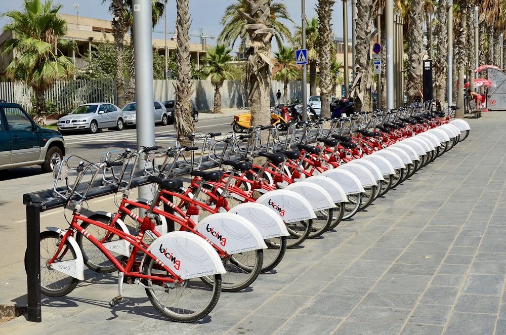 Una hilera de bicicletas rojas y blancas estacionadas una al lado de la otra