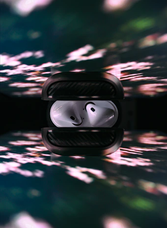 A set of wireless earbuds resting on a charging case with subtle reflections.