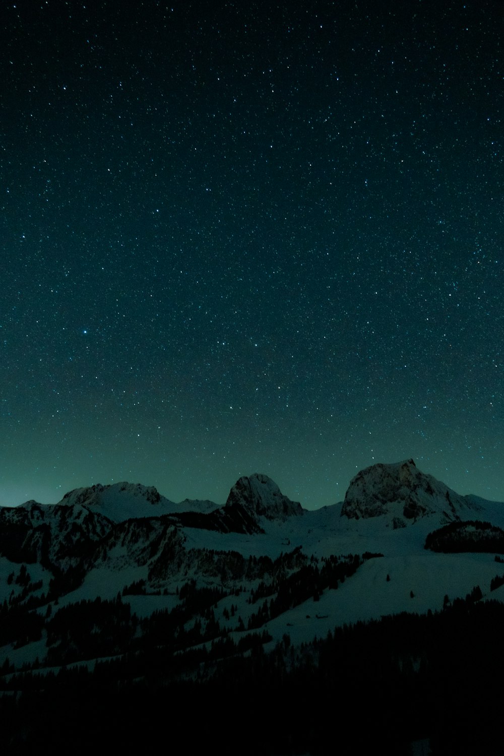 a night sky with stars above a mountain range
