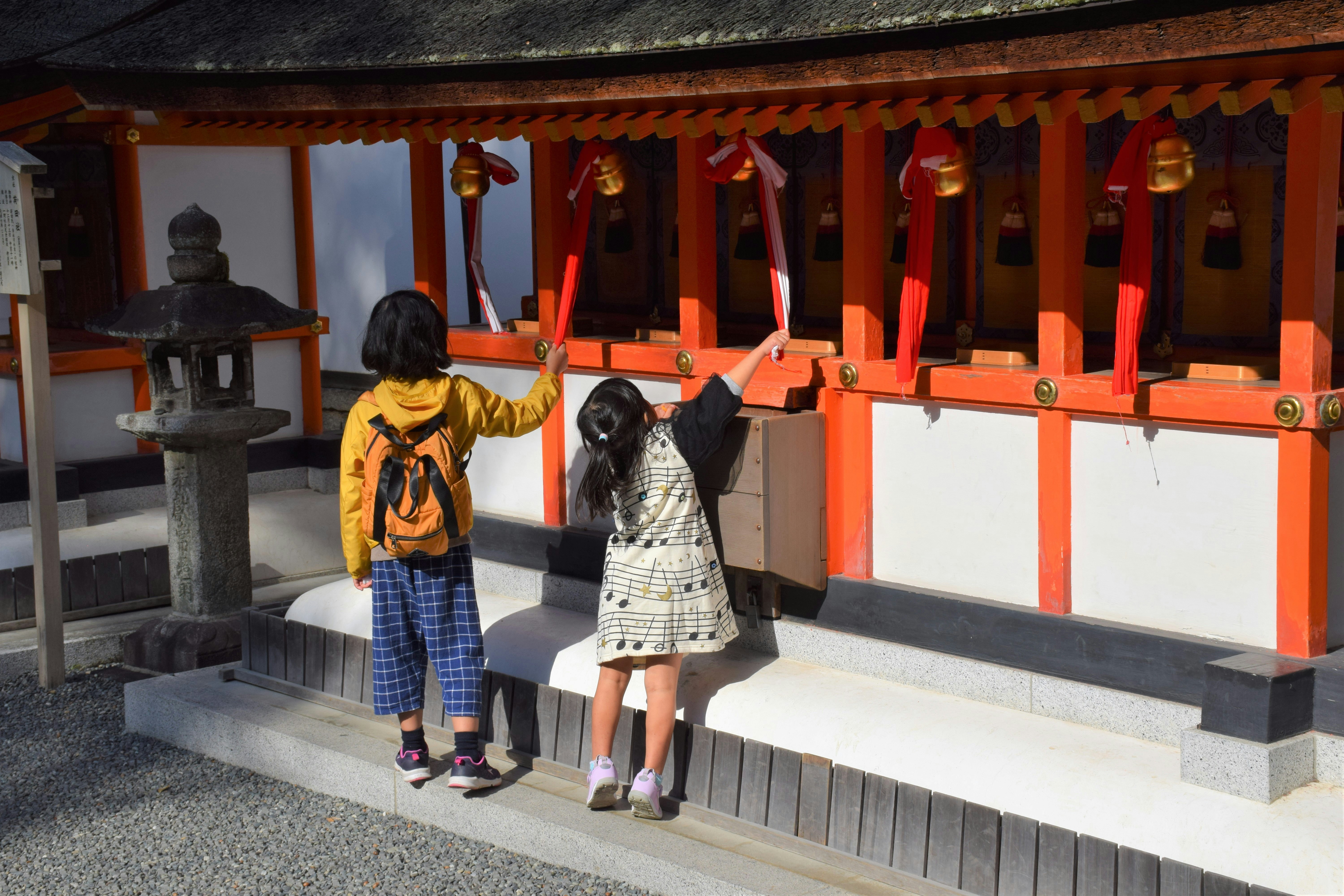 person bowing and clapping hands in front of shrine main hall