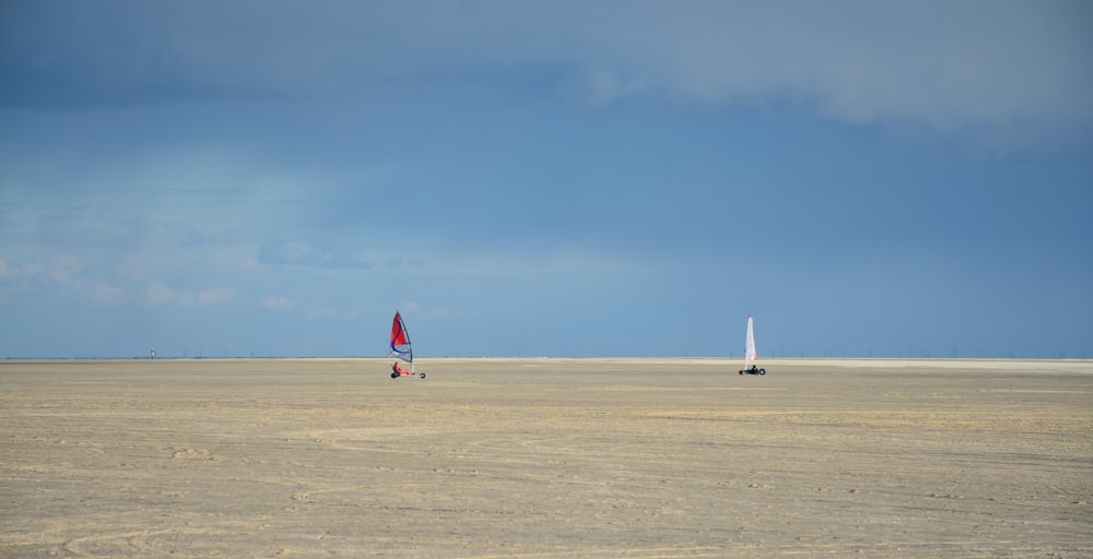 two sailboats in the distance on a sandy beach