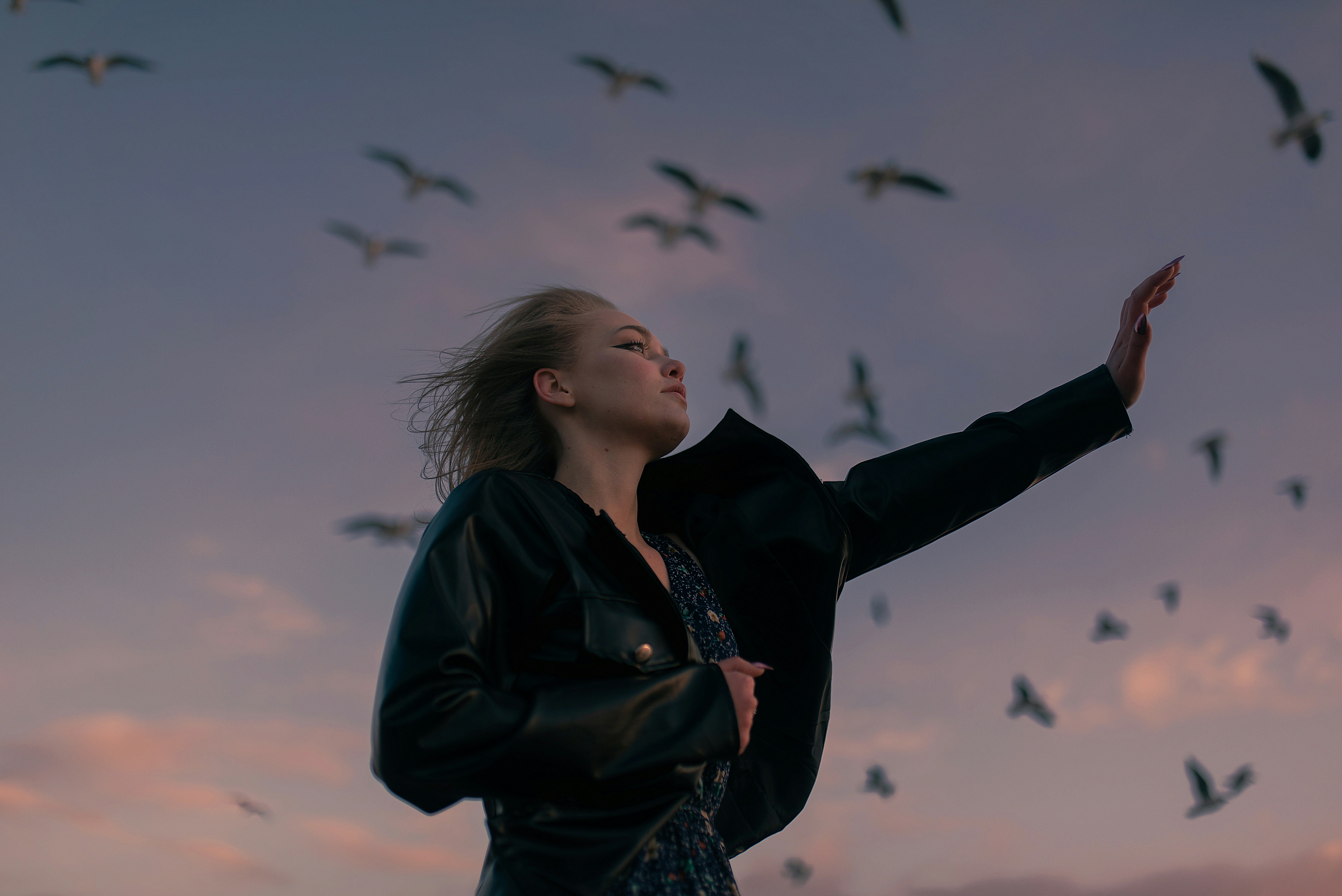a woman standing in front of a flock of birds