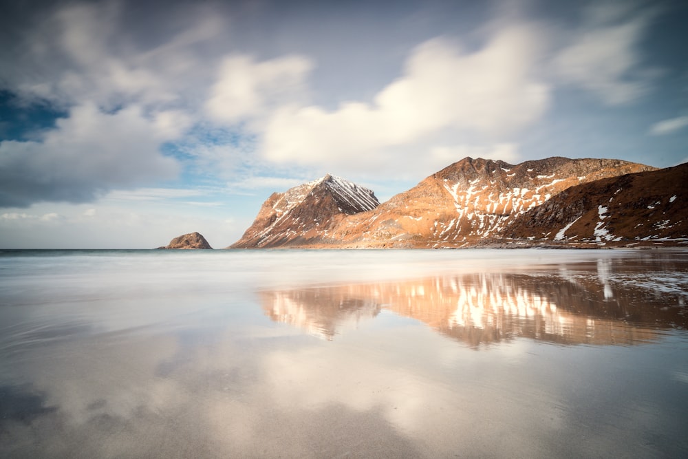 a mountain range is reflected in the still water of a lake