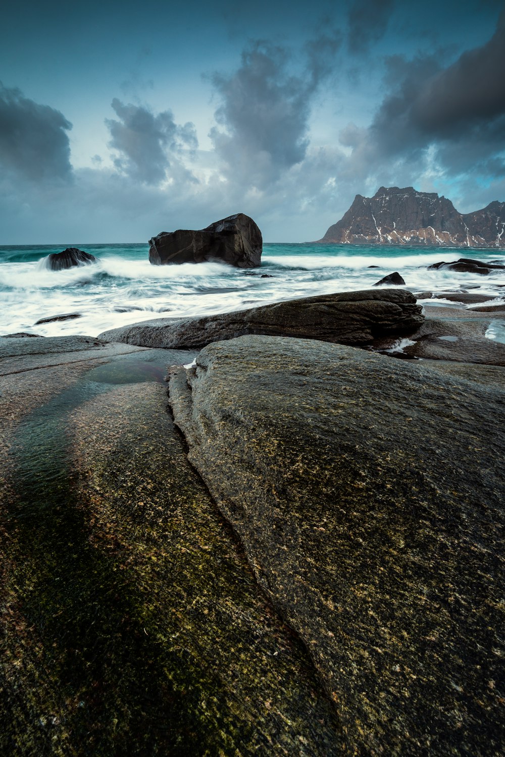 un gros rocher assis au sommet d’une plage au bord de l’océan