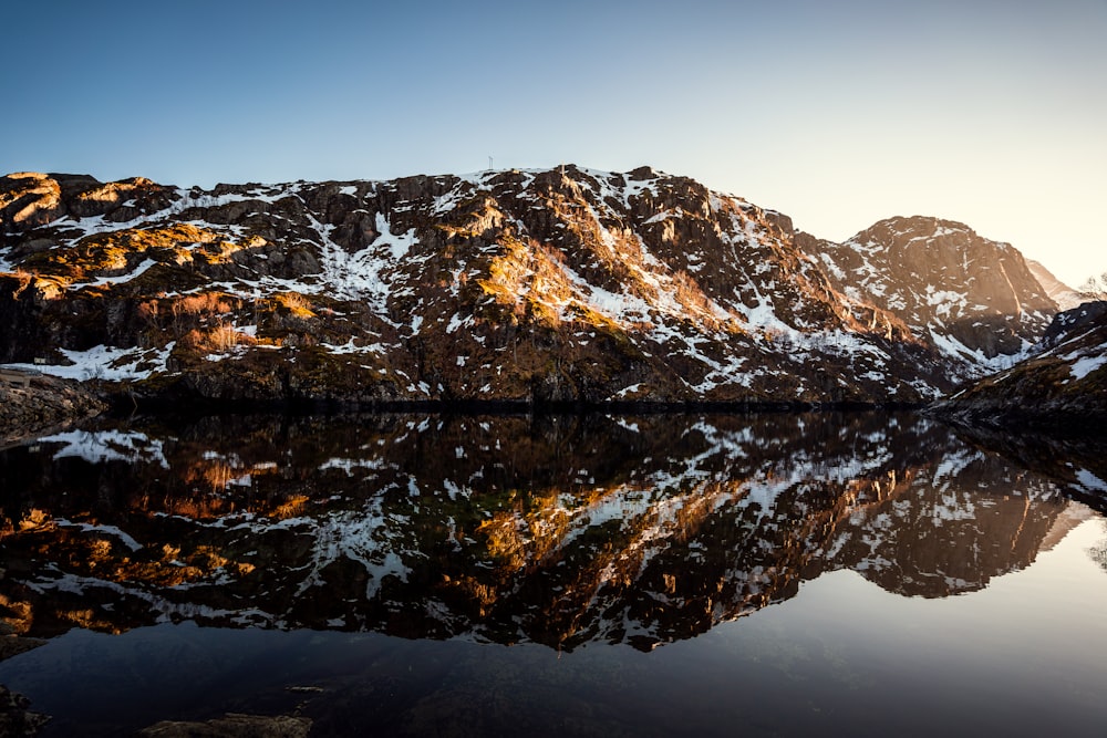 a snow covered mountain with a lake in the foreground