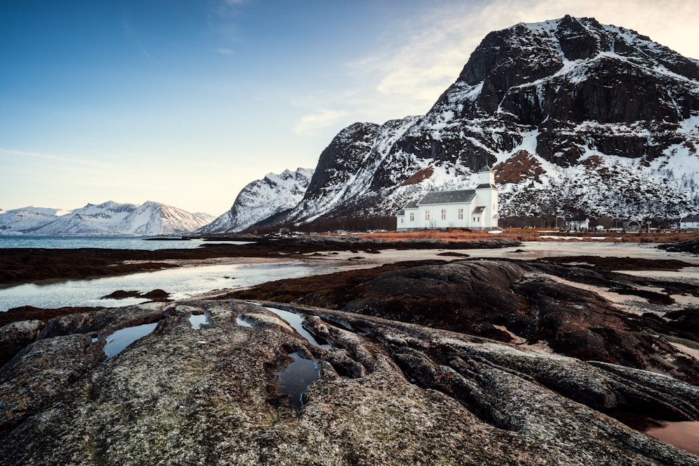 a house on a rocky shore with mountains in the background