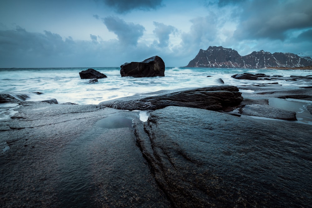 a rocky beach with a large rock in the middle of it