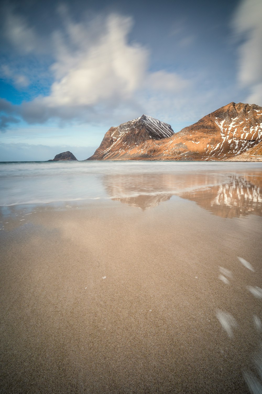 a sandy beach with a mountain in the background