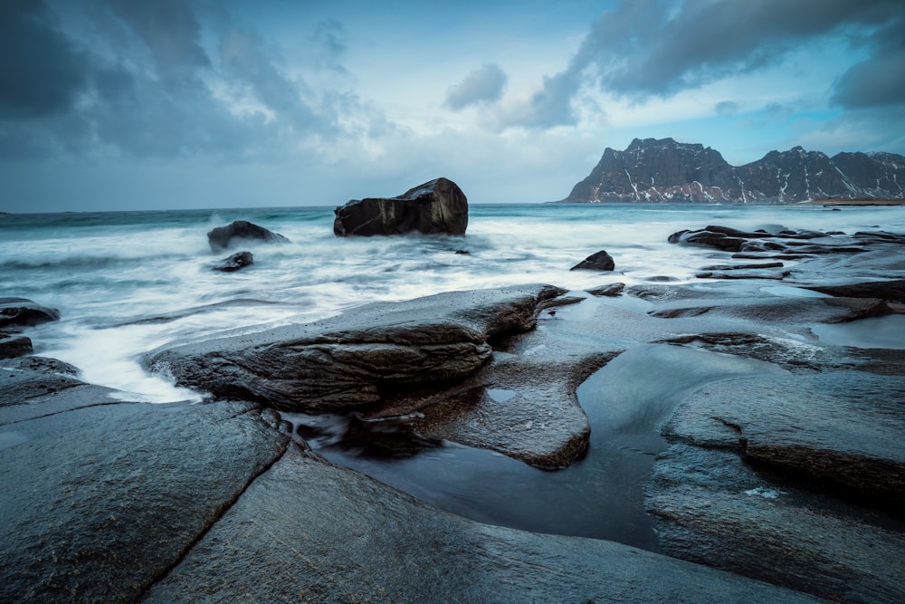 a rocky beach with a large rock in the middle of it