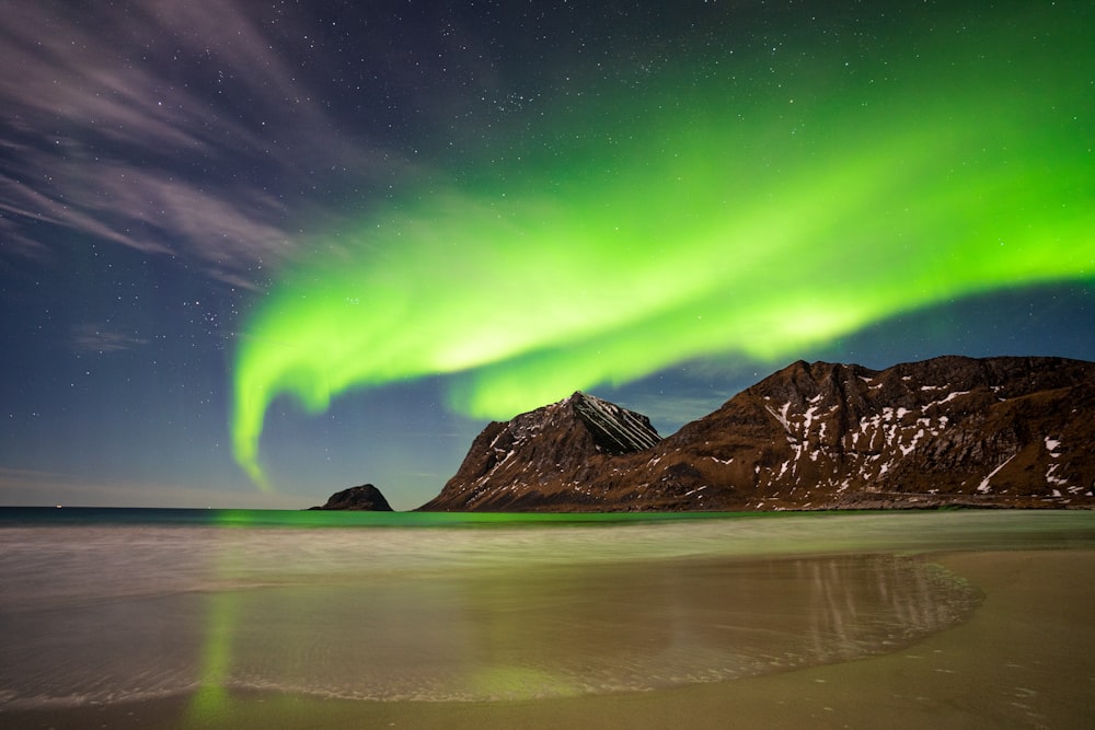 uma aurora verde e roxa pairava sobre uma montanha