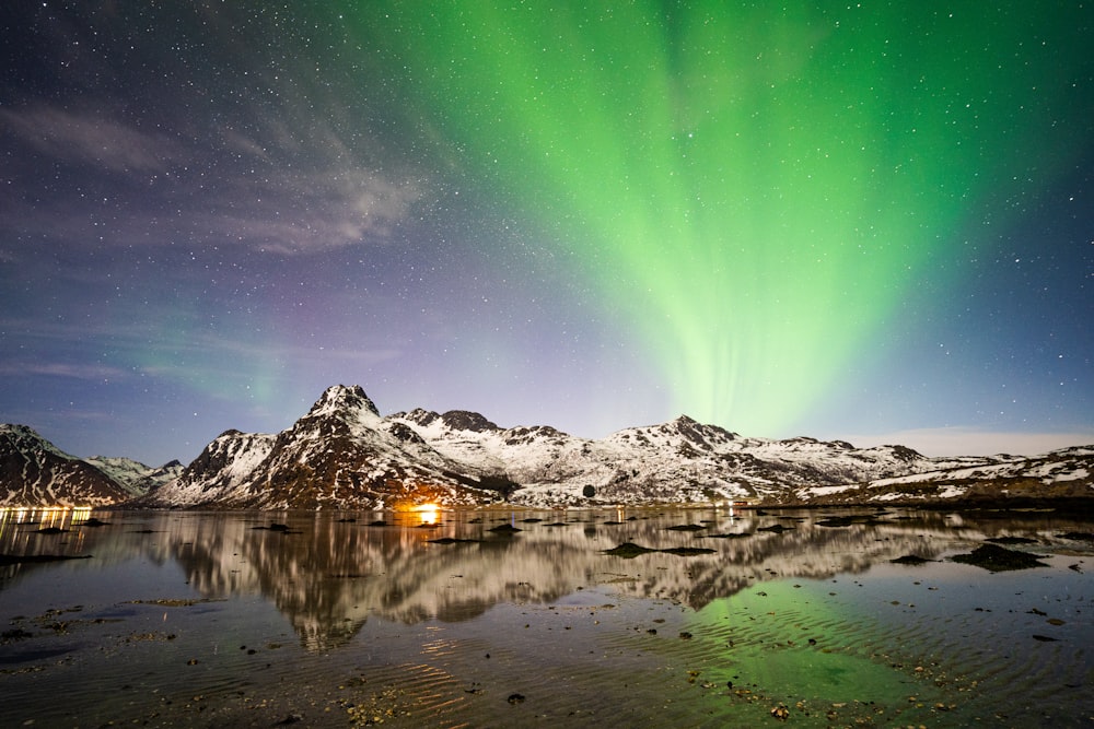 a green and white aurora bore above a mountain range