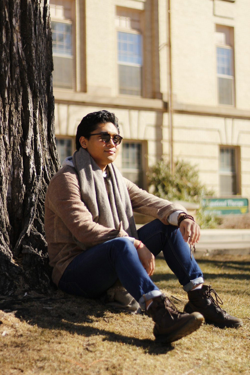 a man sitting on the ground next to a tree