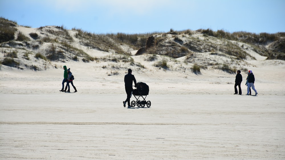 a group of people walking across a sandy beach