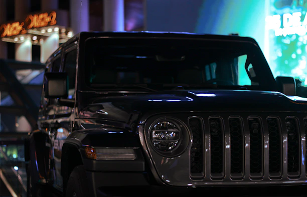 A sleek black SUV parked curbside at Harry Reid International Airport under warm evening lights.