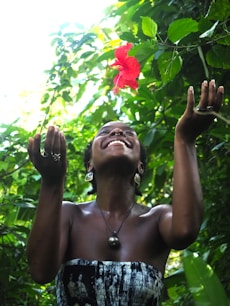 a woman standing in front of a red flower