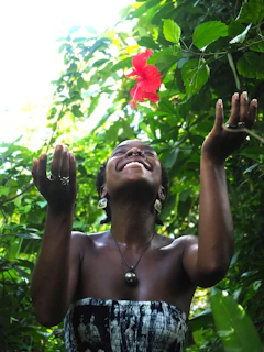 a woman standing in front of a red flower