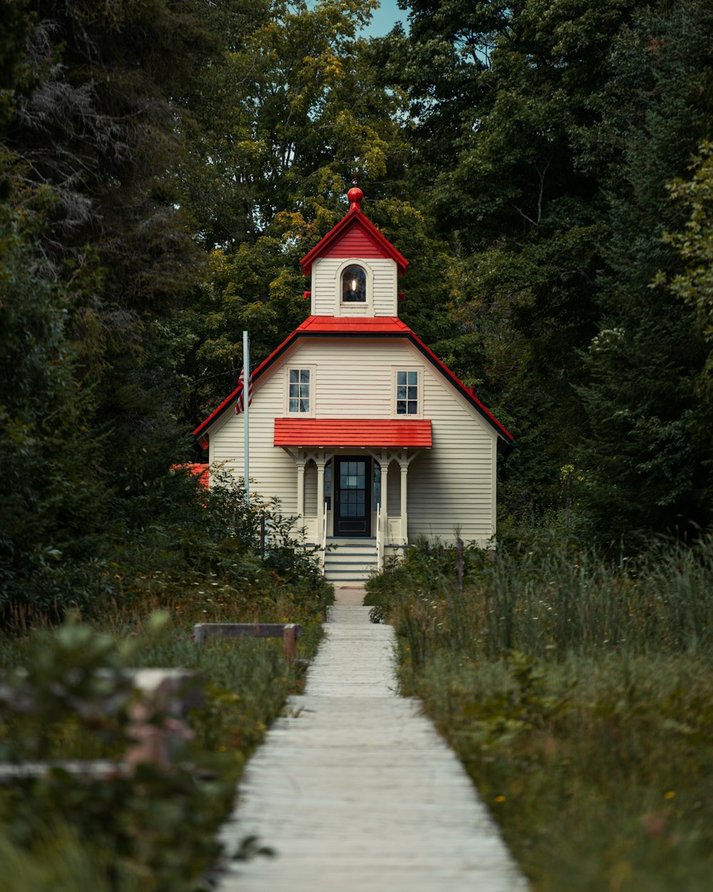 a white church with a red roof surrounded by trees