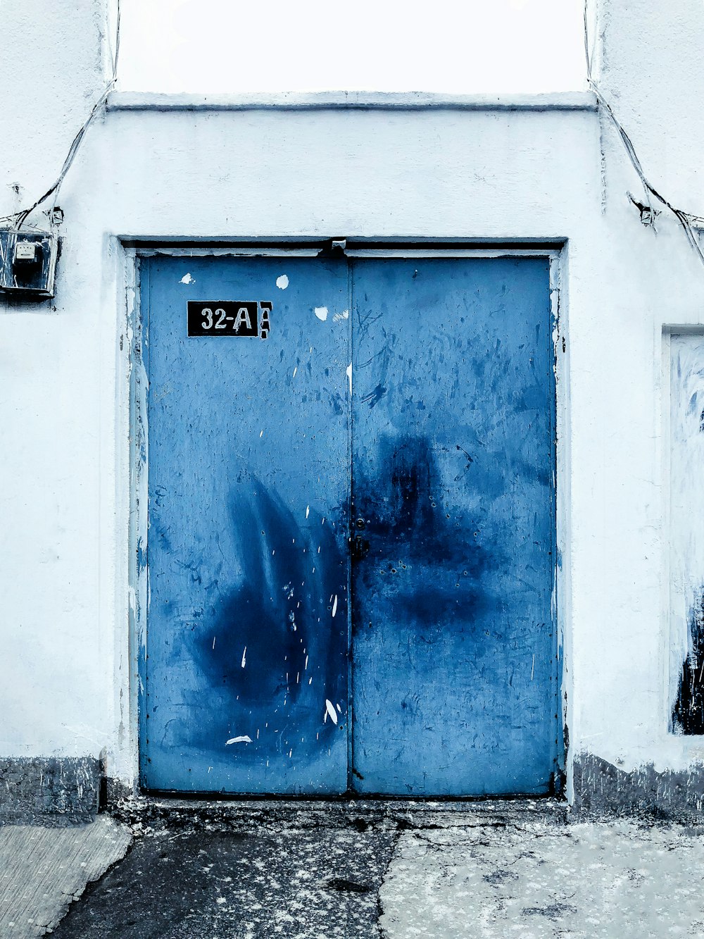 Una porta blu su un edificio bianco con graffiti su di esso