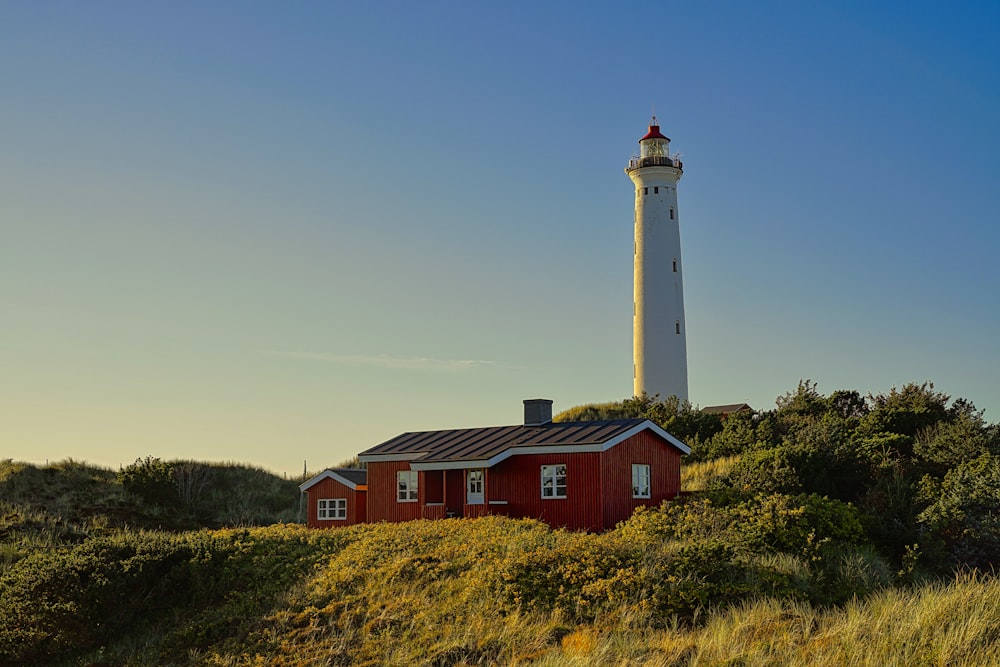 a red house with a white lighthouse on top of a hill
