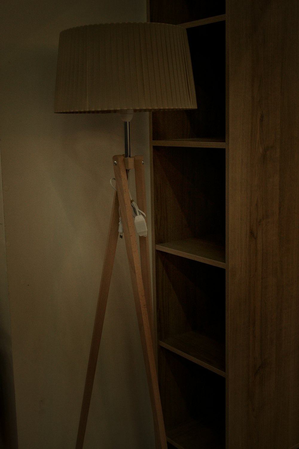 a wooden floor lamp next to a book shelf