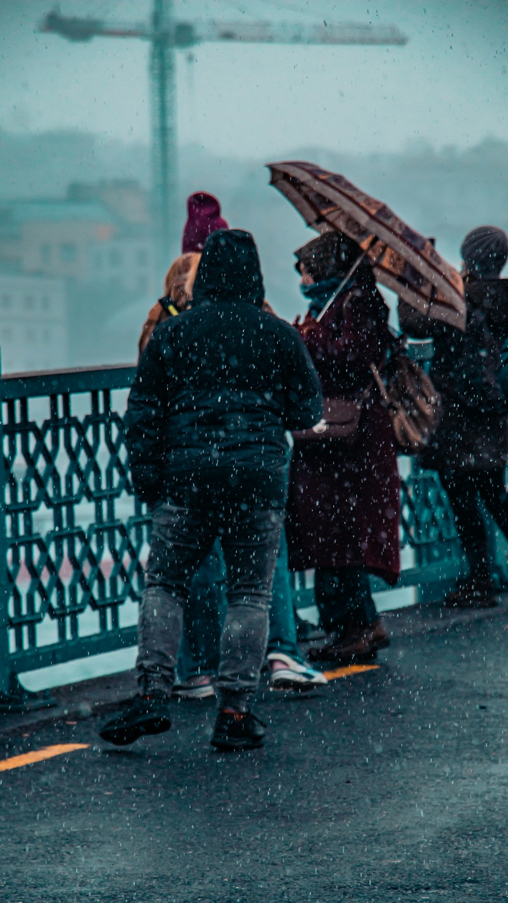 a group of people standing on a bridge in the rain