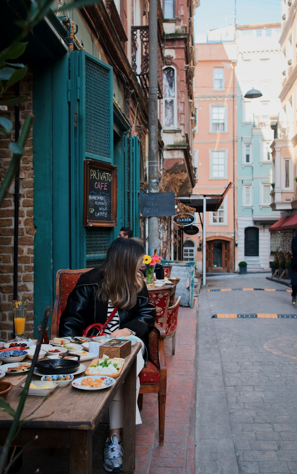 a woman sitting at a table outside of a restaurant