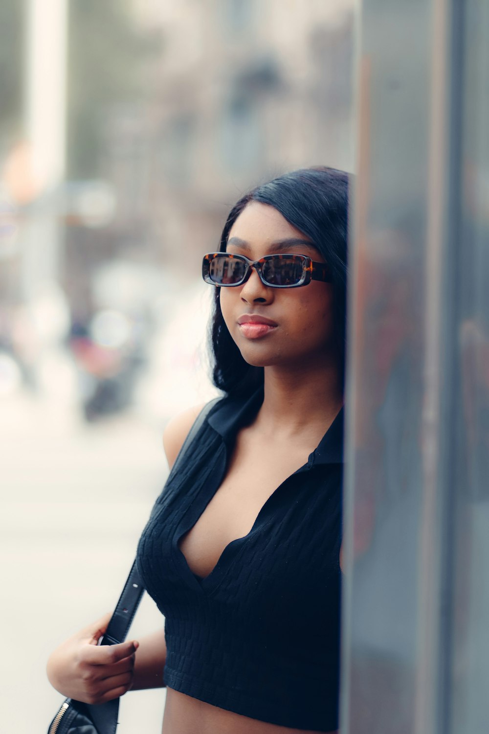 a woman wearing sunglasses leaning against a wall